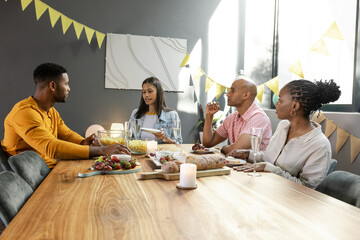 Friends enjoying dinner party at home, sharing stories and laughter around table