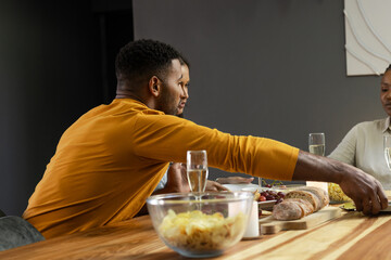 Friends enjoying dinner together, sharing food and drinks at cozy dining table