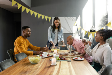 Friends enjoying dinner party at home, sharing food and laughter around table