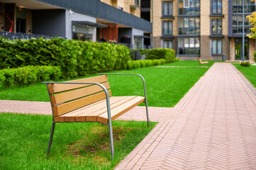 modern urban park bench on lush green lawn near residential building showcasing contemporary...
