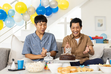 Celebrating birthday, two friends clapping and smiling with cake in living room