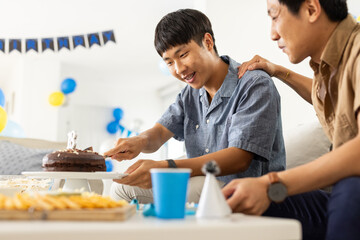 Father and son celebrating birthday at home, cutting chocolate cake together