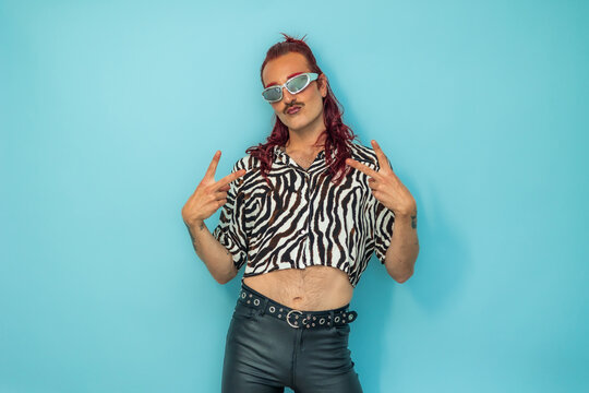 Non-binary person gesturing peace sign on blue background