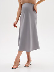 Pregnant girl model in stylish clothes on a colorless background in the studio.