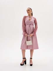 Pregnant girl model in stylish clothes on a colorless background in the studio.