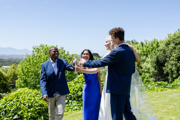 Celebrating wedding outdoors, friends toasting with champagne and smiling together