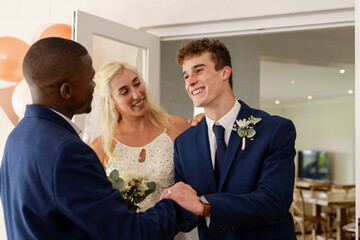 Bride and groom joyfully greeting guest at elegant indoor wedding celebration