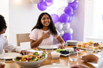 Smiling girl expressing gratitude at family celebration with food and decorations