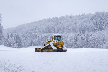 Snow-covered landscape with a bulldozer clearing a path in a winter wonderland © andov