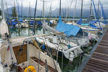 Sailboats anchored at a scenic marina surrounded by mountains on a cloudy day