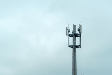Obraz premium Cell tower rises above trees under cloudy sky at midday in a suburban area