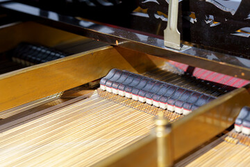 Detail of piano interior illustrating strings, hammers, and craftsmanship in soft lighting during...