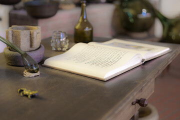 Open notebook on a wooden table with glassware in a traditional workshop setting during the day