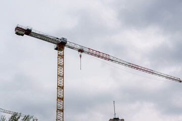 Construction crane towers over a city skyline during overcast weather and potential rain