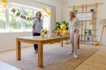 Senior friends preparing retirement party table with decorations and refreshments
