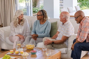 Senior friends enjoying conversation and snacks together in cozy living room