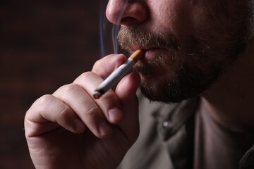 Man smoking cigarette on blurred background, closeup