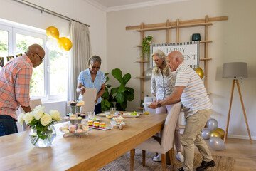 Senior friends arranging table with cupcakes and snacks for birthday celebration