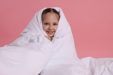 Cute girl with blanket on pink background