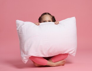 Cute girl with pillow on pink background