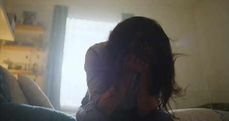 Woman with head in hands, sitting on bed in emotional distress, private and reflective moment,...