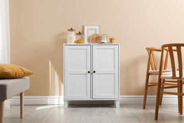 Dresser with stylish decor near beige wall indoors