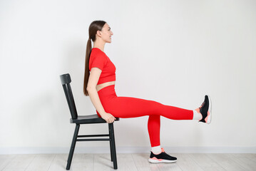 Beautiful woman exercising with chair at home