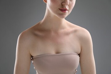 Woman with beautiful collarbones on grey background, closeup