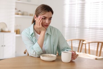 Depressed woman with appetite loss at table indoors