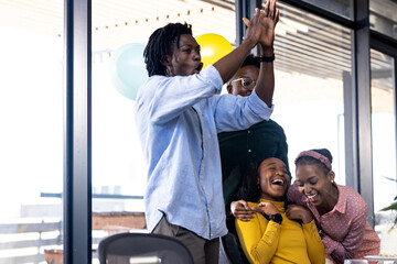 Celebrating success, diverse team clapping and laughing in modern office space