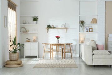 Stylish dining table with chairs and comfortable sofa in room. Interior design