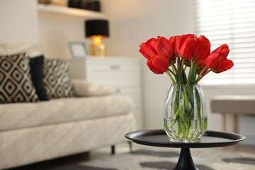 Beautiful red tulips in vase on table indoors, space for text