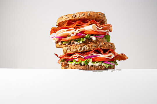 Stacked gourmet sandwiches on a white background