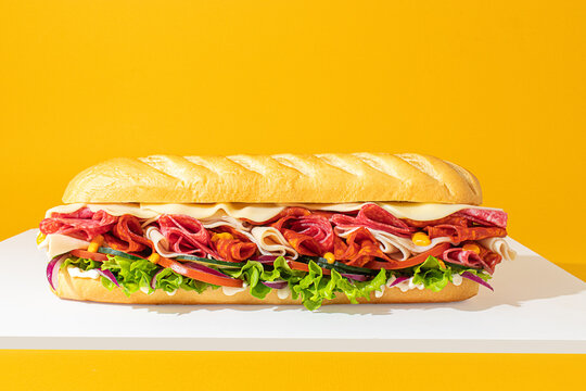 Sub sandwich with layers of meat and veggies, isolated on bright background