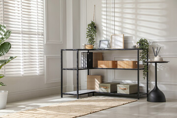 Console table with different decor near white wall indoors. Interior design