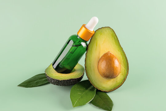 Avocado Oil and Fresh Avocado on Green Background