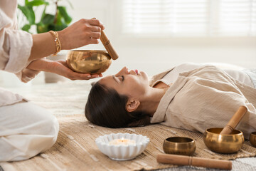 Woman undergoing singing bowl therapy lying on floor indoors