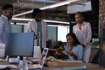 Celebrating colleague's achievement, African American team in modern office environment