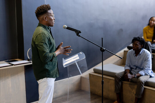Giving presentation, African American man engaging audience in modern office space