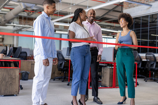 Celebrating office opening, diverse business team cutting ribbon, smiling together