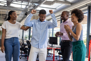 Colleagues celebrating success in modern office, smiling and clapping with joy