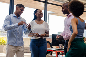 Colleagues in office discussing project, smiling and engaging in lively conversation