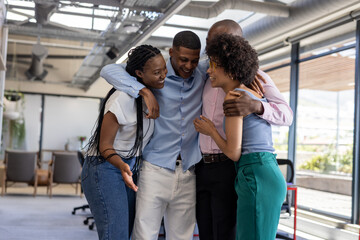 Obraz premium Diverse colleagues in office hugging and laughing, celebrating team success together