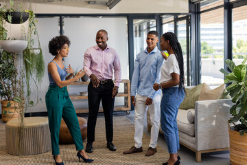 Colleagues in office discussing project, smiling and engaging in lively conversation