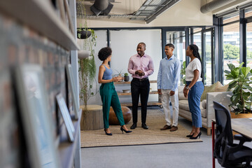 Fototapeta premium In office, professionals standing together discussing project with positive expressions