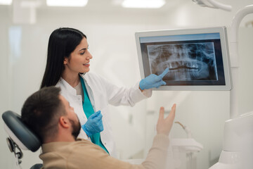 Dentist showing teeth x ray to patient in modern clinic
