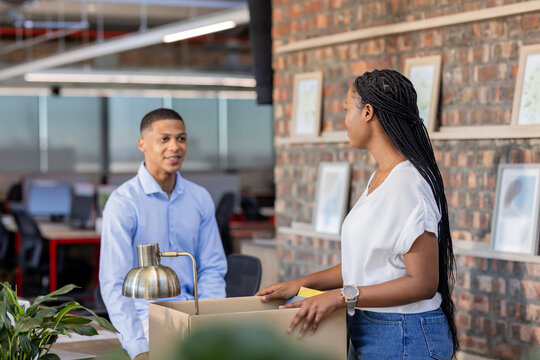 African American colleagues discussing project while unpacking box in modern office