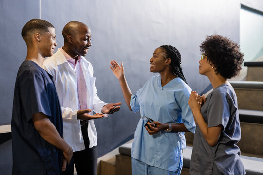 Discussing patient care, African American medical professionals smiling in hospital hallway