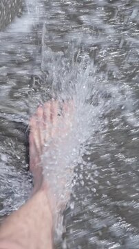 Vertical screen. Crystal-clear seawater gently washes over a tourist's foot as they explore the unique black magnetic sand beach of Ureki on the Georgian Black Sea coast. Travel tour. Background