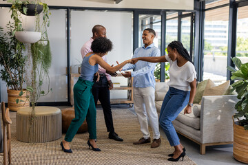 Colleagues greeting each other with enthusiasm in modern office lounge area